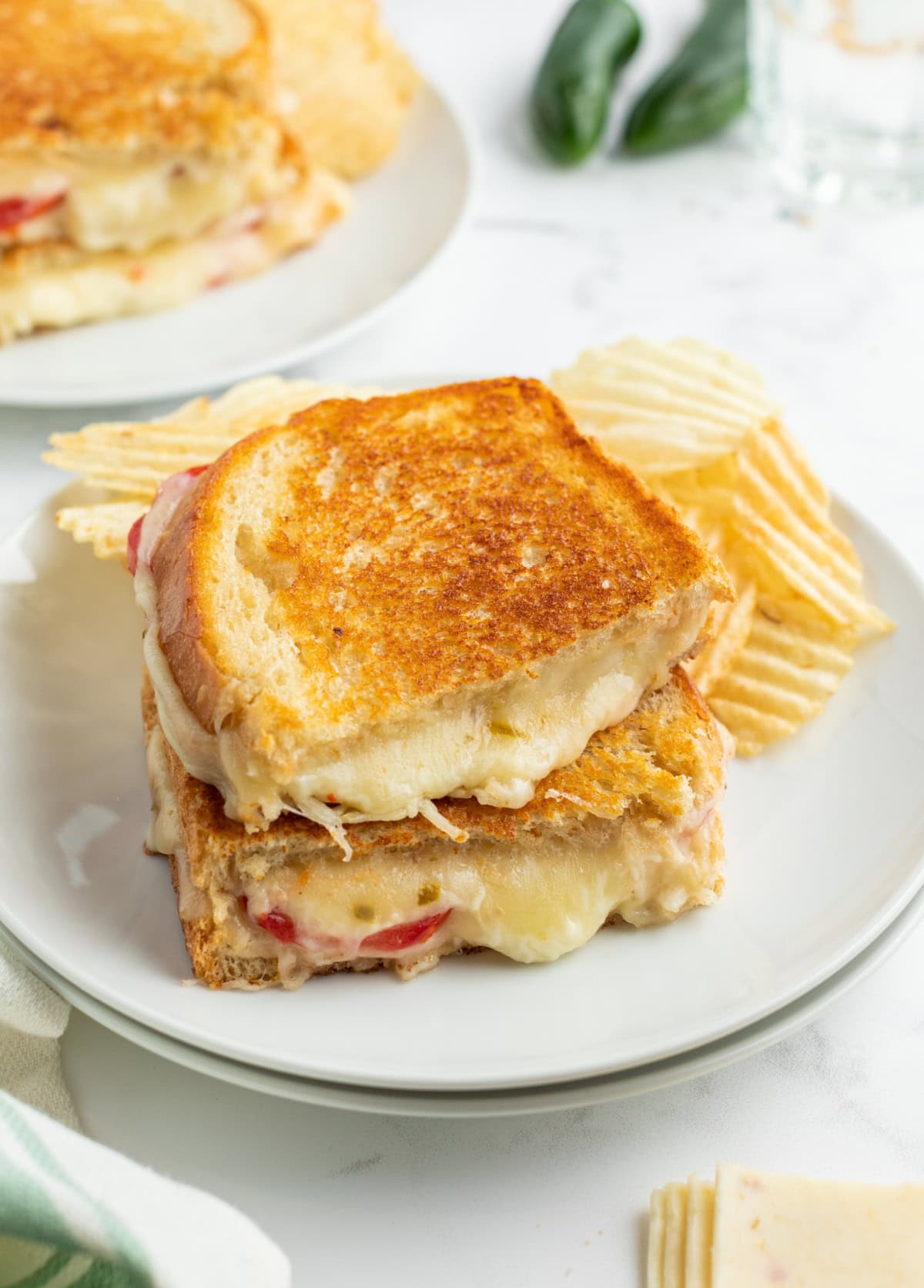 two halves of a tomato grilled cheese stacked on a plate with cheese gushing out