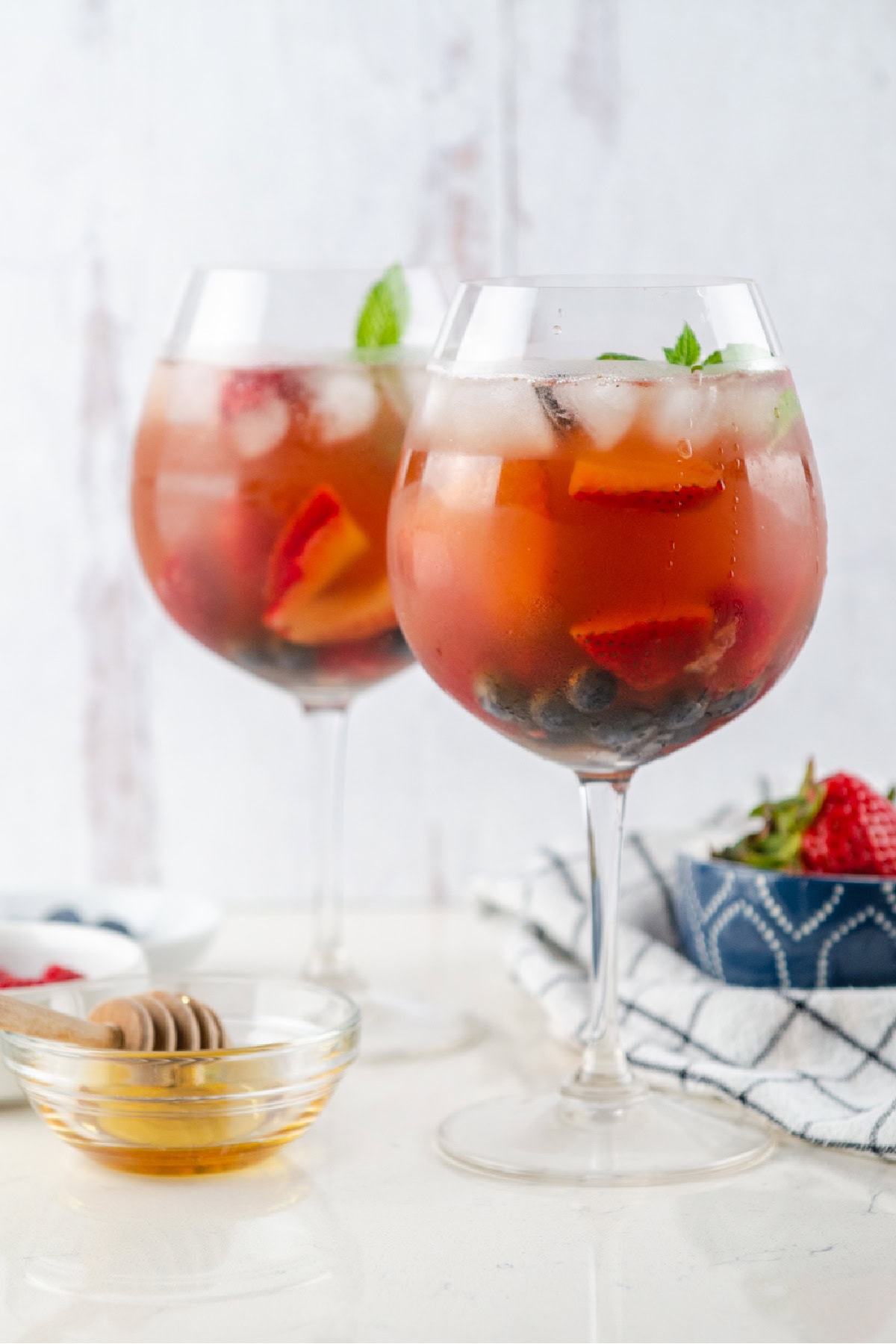 Berry iced tea sangria with white wine, fresh berries and honey. Light, refreshing and perfect for summer! two glassess of berry iced tea sangria