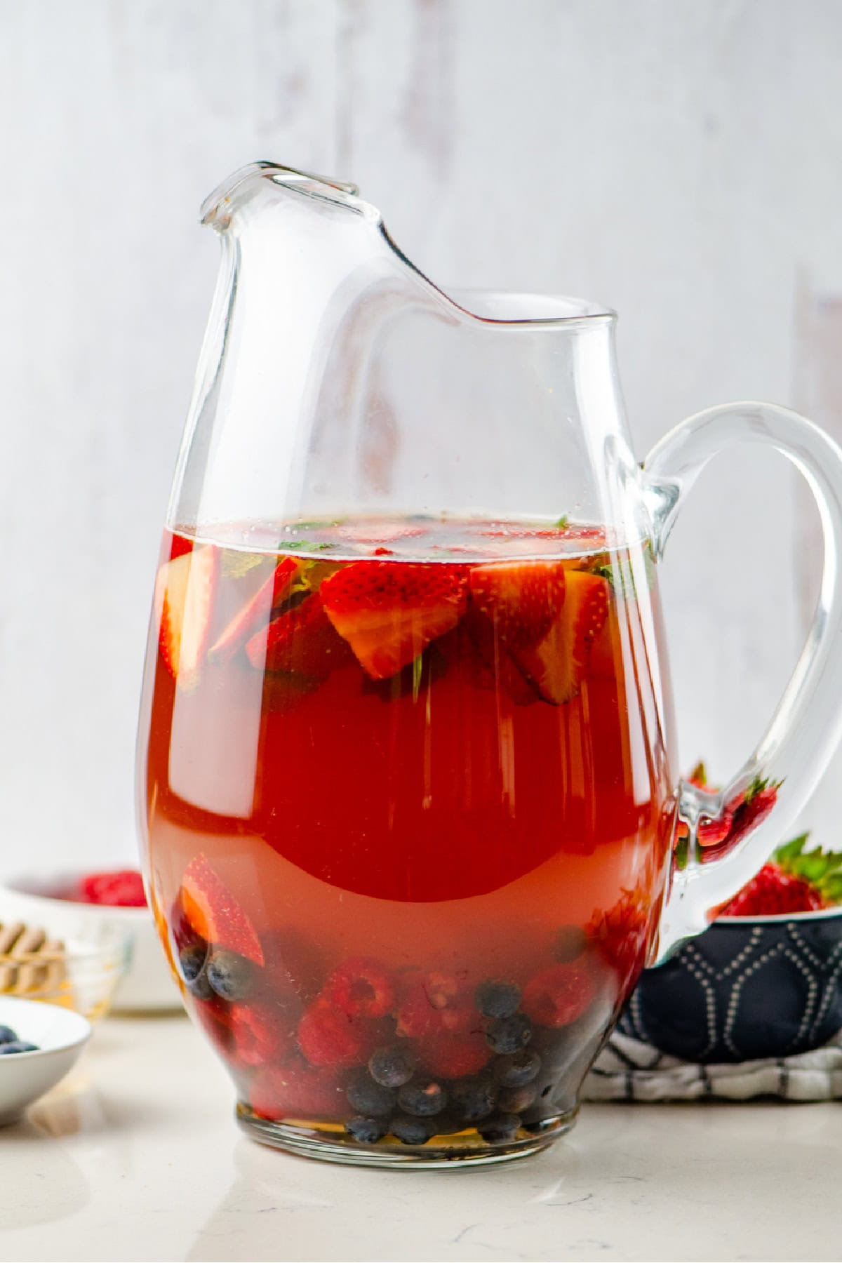 Berry iced tea sangria with white wine, fresh berries and honey. Light, refreshing and perfect for summer! pitcher of berry iced tea sangria