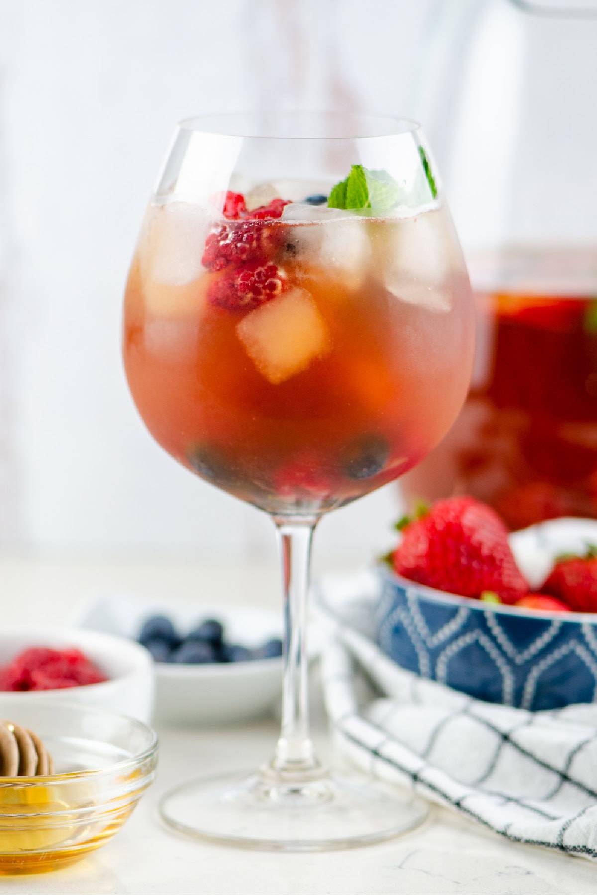 Berry iced tea sangria with white wine, fresh berries and honey. Light, refreshing and perfect for summer! glass filled with berry iced tea sangria