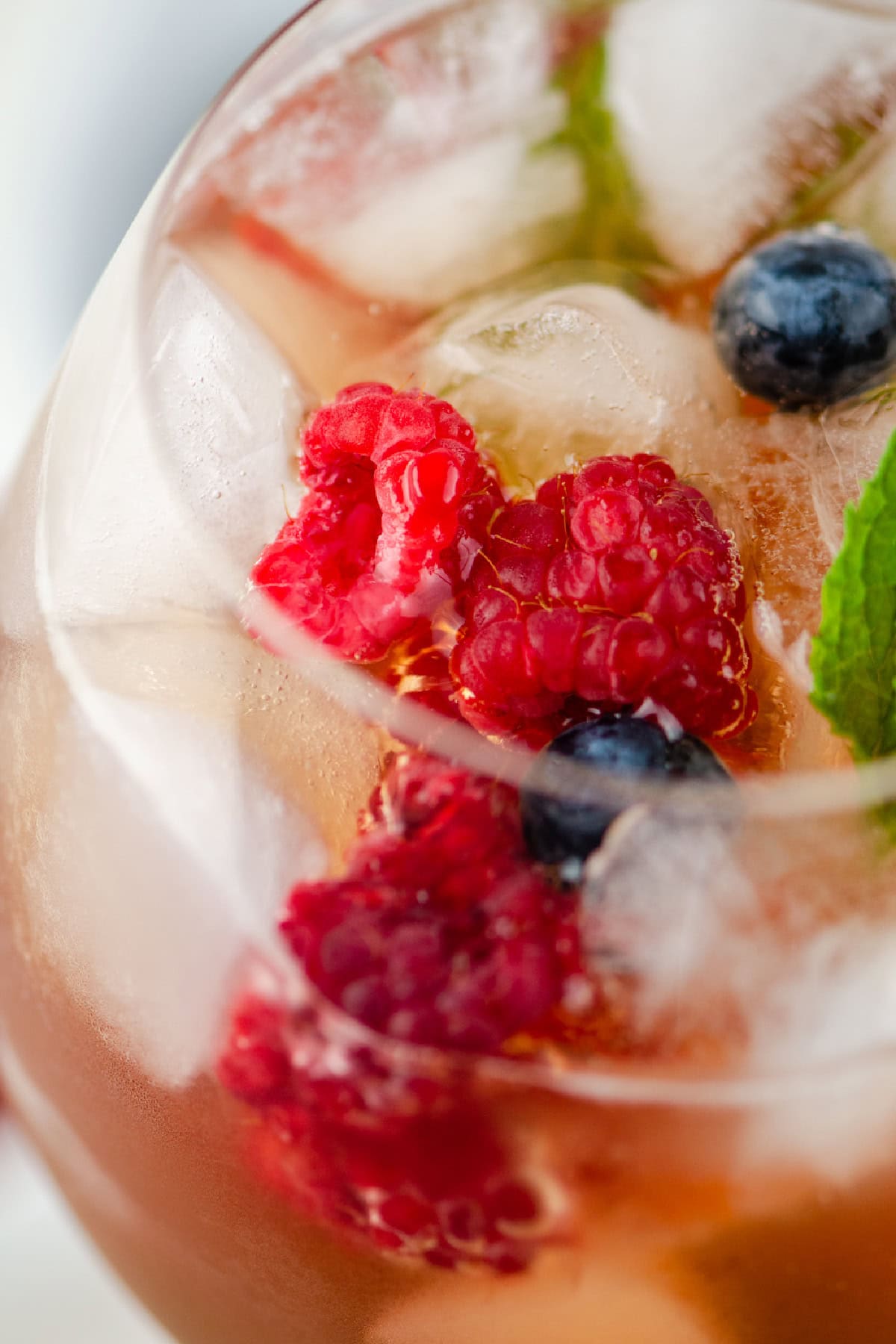 Berry iced tea sangria with white wine, fresh berries and honey. Light, refreshing and perfect for summer! close up of berry iced tea sangria