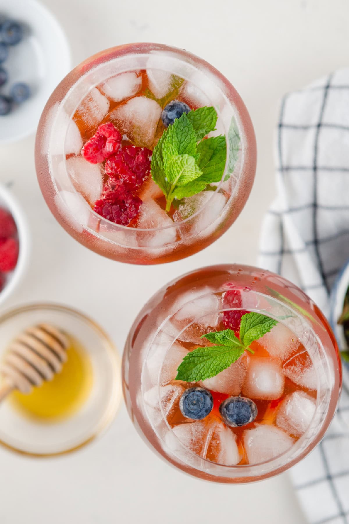 Berry iced tea sangria with white wine, fresh berries and honey. Light, refreshing and perfect for summer! overhead shot of two glassses of berry iced tea sangria