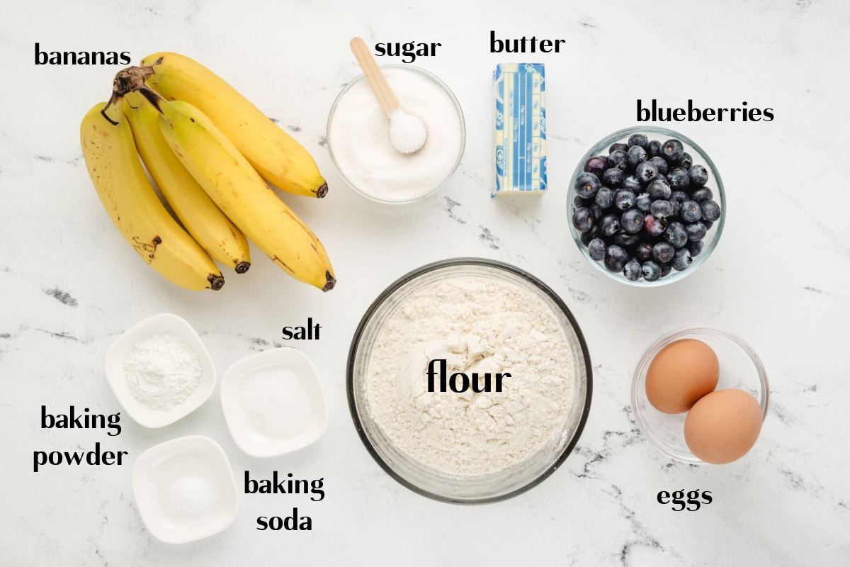 This Blueberry Banana Bread is soft, moist and bursting with juicy blueberries and sweet ripe bananas! It's an easy homemade quick bread that's perfect for breakfast, brunch, snacks or freezing for later. Save this delicious loaf recipe! 🍌🫐 #bananabread #blueberrybananabread #quickbread #breakfastrecipes #homemadebread ingredients displayed for making blueberry banana bread