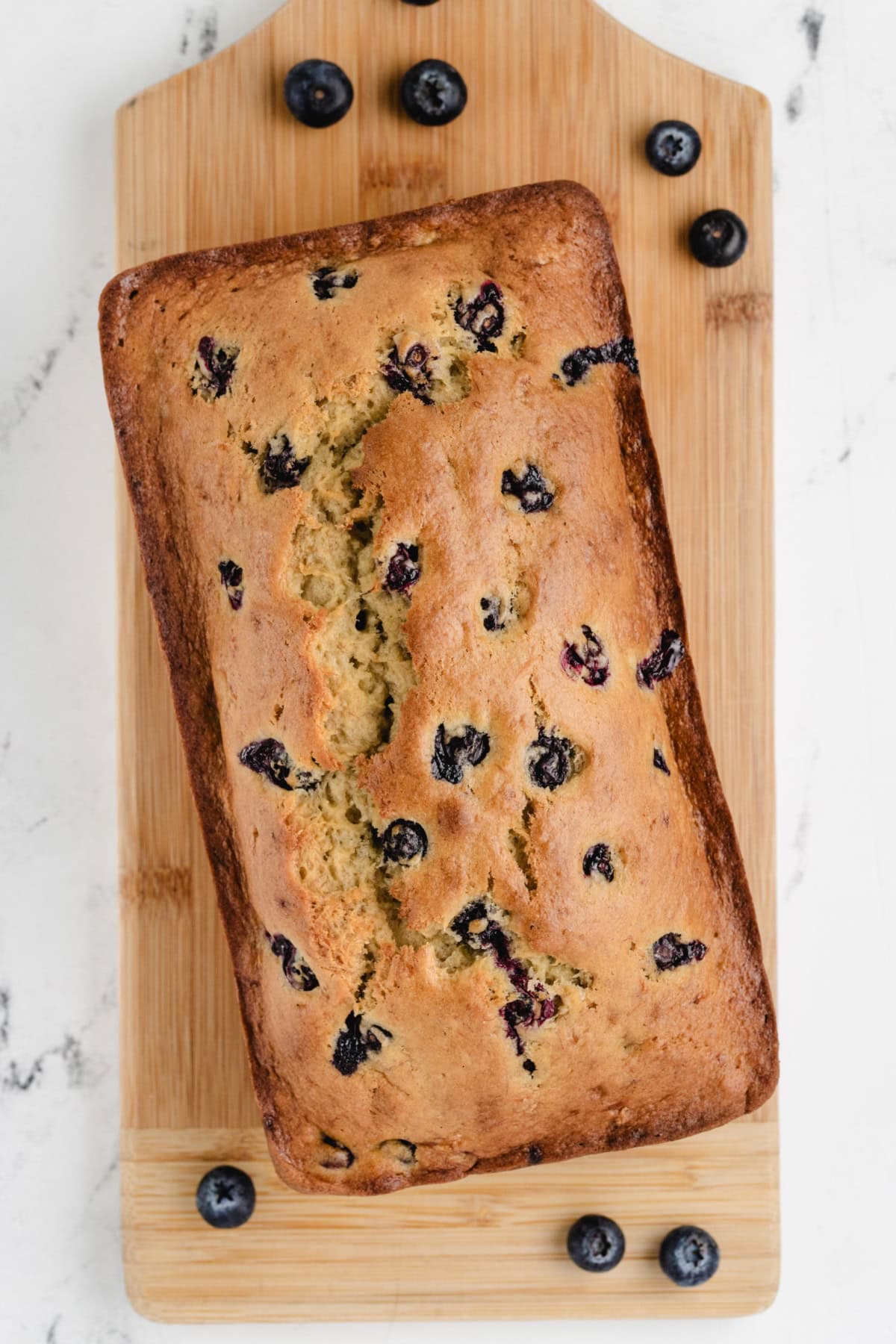 This Blueberry Banana Bread is soft, moist and bursting with juicy blueberries and sweet ripe bananas! It's an easy homemade quick bread that's perfect for breakfast, brunch, snacks or freezing for later. Save this delicious loaf recipe! 🍌🫐 #bananabread #blueberrybananabread #quickbread #breakfastrecipes #homemadebread overhead shoot of blueberry banana bread loaf
