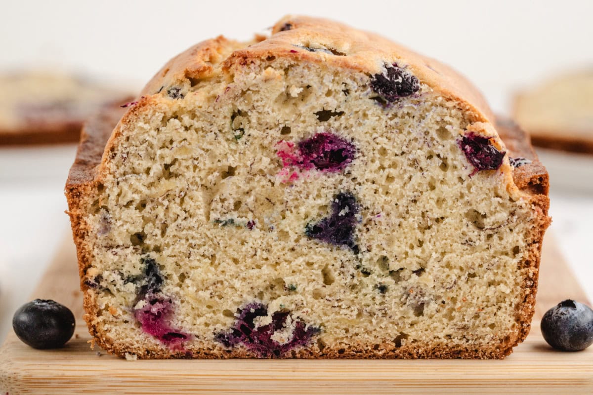 This Blueberry Banana Bread is soft, moist and bursting with juicy blueberries and sweet ripe bananas! It's an easy homemade quick bread that's perfect for breakfast, brunch, snacks or freezing for later. Save this delicious loaf recipe! 🍌🫐 #bananabread #blueberrybananabread #quickbread #breakfastrecipes #homemadebread peek at the inside of a loaf of blueberry banana bread