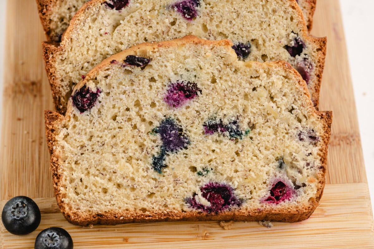 This Blueberry Banana Bread is soft, moist and bursting with juicy blueberries and sweet ripe bananas! It's an easy homemade quick bread that's perfect for breakfast, brunch, snacks or freezing for later. Save this delicious loaf recipe! 🍌🫐 #bananabread #blueberrybananabread #quickbread #breakfastrecipes #homemadebread slices of blueberry banana bread