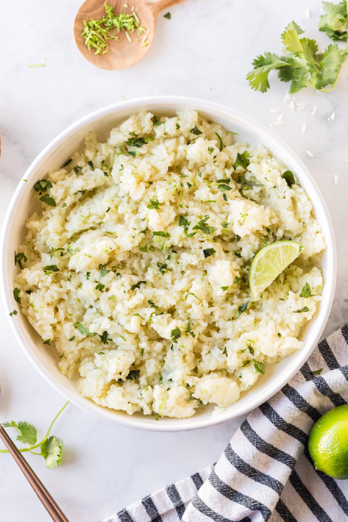 This easy Lime and Cilantro Rice is packed with fresh lime juice, lime zest, cilantro and savory seasonings for incredible flavor. Perfect for tacos, burrito bowls, enchiladas, fajitas and more. Save this restaurant-style rice recipe for your next Mexican dinner night! #cilantrolimerice #mexicanrecipes #rice #sidedish #taconight bowl of lime and cilantro rice