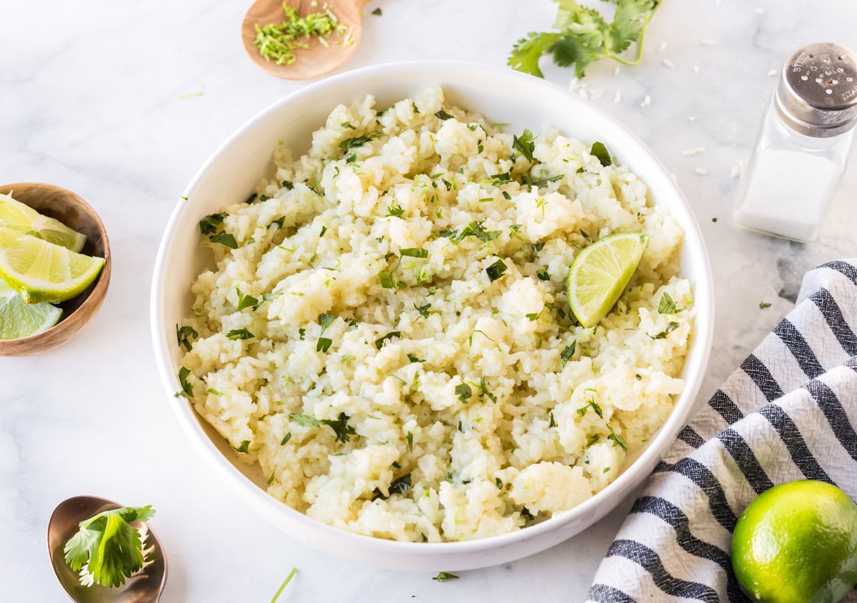This easy Lime and Cilantro Rice is packed with fresh lime juice, lime zest, cilantro and savory seasonings for incredible flavor. Perfect for tacos, burrito bowls, enchiladas, fajitas and more. Save this restaurant-style rice recipe for your next Mexican dinner night! #cilantrolimerice #mexicanrecipes #rice #sidedish #taconight bowl of lime and cilantro rice