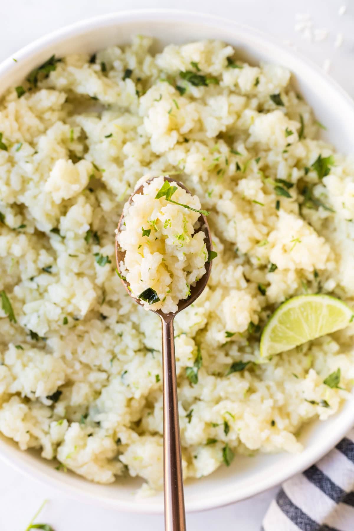 This easy Lime and Cilantro Rice is packed with fresh lime juice, lime zest, cilantro and savory seasonings for incredible flavor. Perfect for tacos, burrito bowls, enchiladas, fajitas and more. Save this restaurant-style rice recipe for your next Mexican dinner night! #cilantrolimerice #mexicanrecipes #rice #sidedish #taconight spoon full of lime and cilantro rice