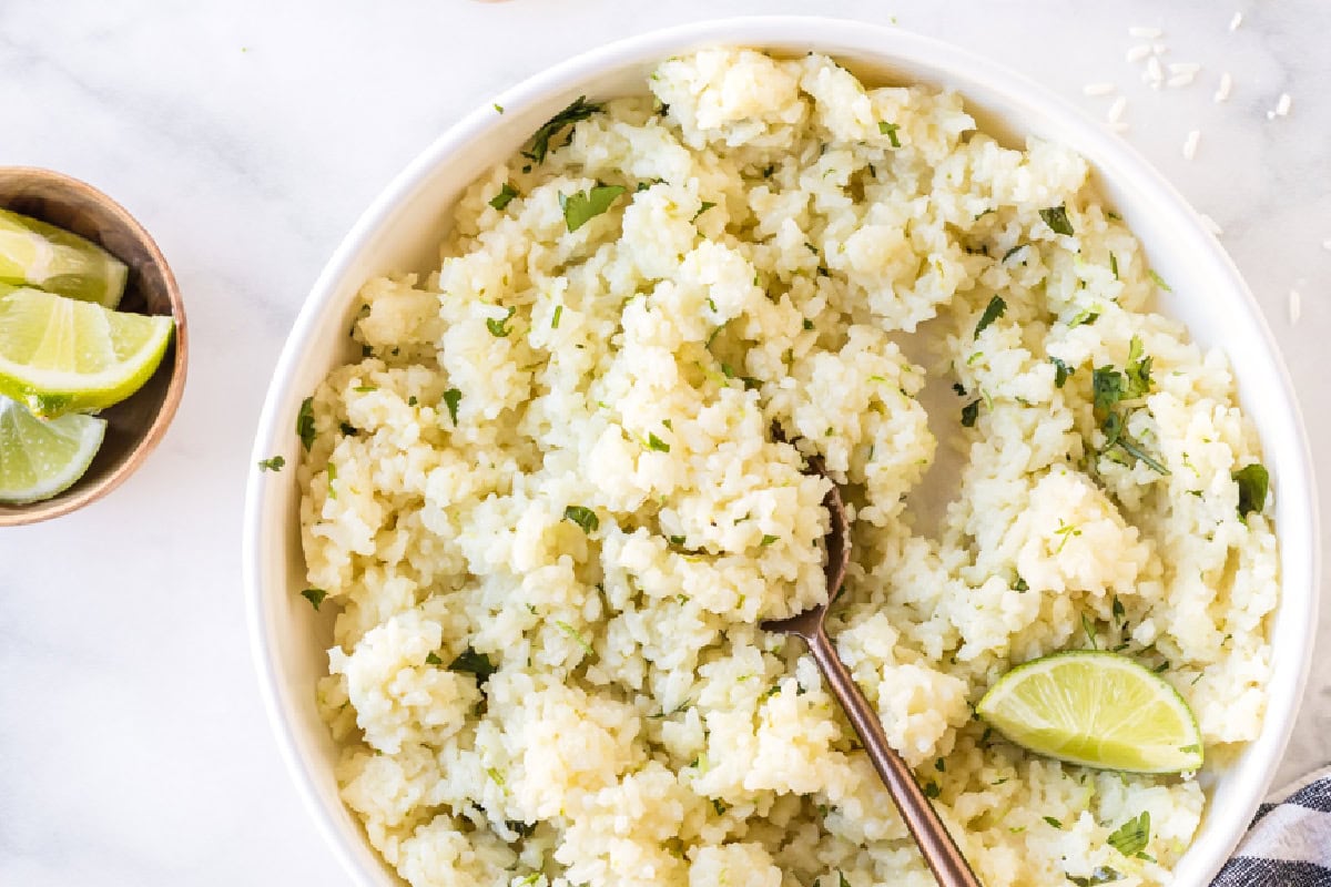 This easy Lime and Cilantro Rice is packed with fresh lime juice, lime zest, cilantro and savory seasonings for incredible flavor. Perfect for tacos, burrito bowls, enchiladas, fajitas and more. Save this restaurant-style rice recipe for your next Mexican dinner night! #cilantrolimerice #mexicanrecipes #rice #sidedish #taconight lime and cilantro rice in bowl