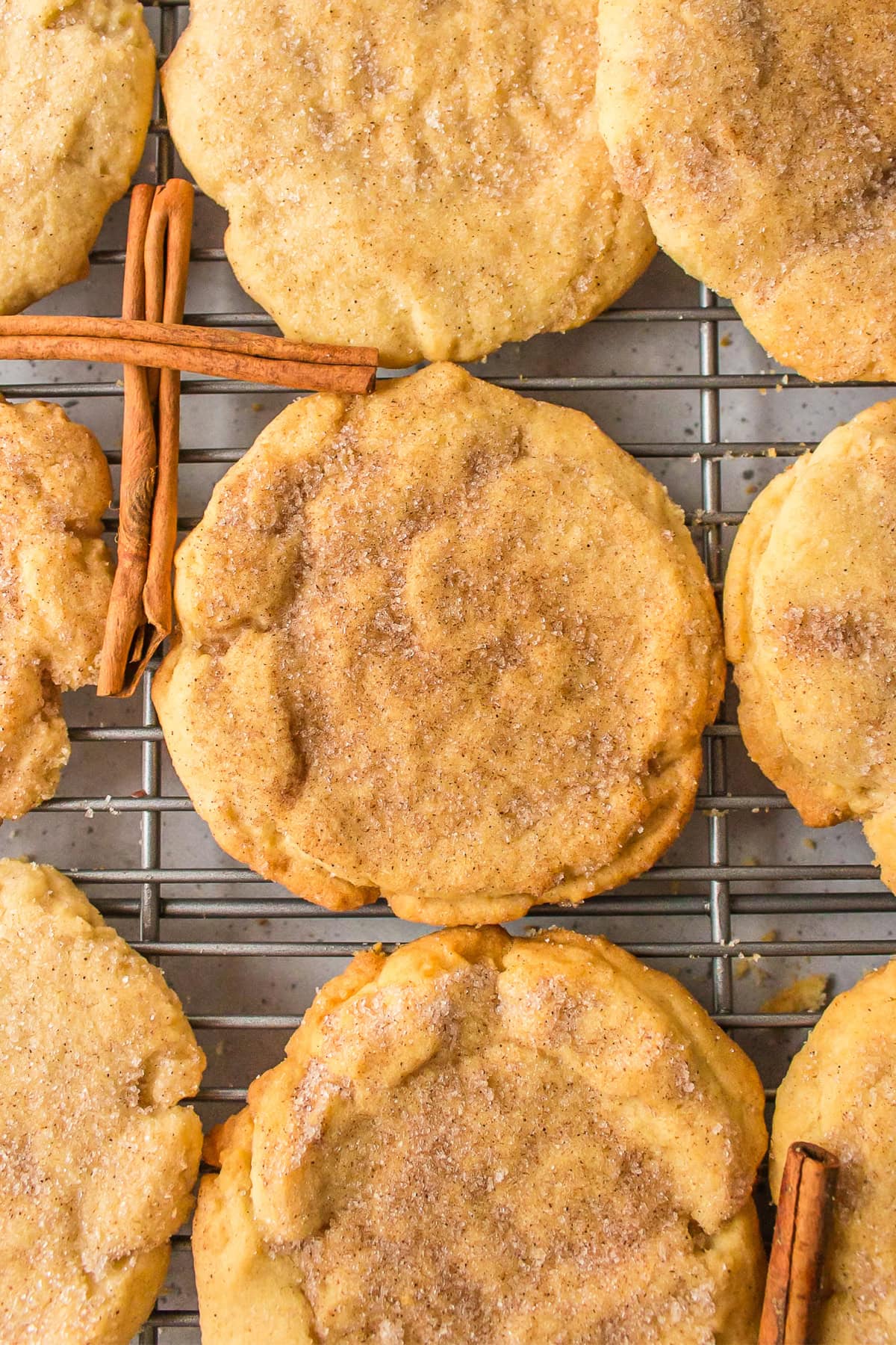 sugar and cinnamon cookies on a cooling rack with cinnamon sticks