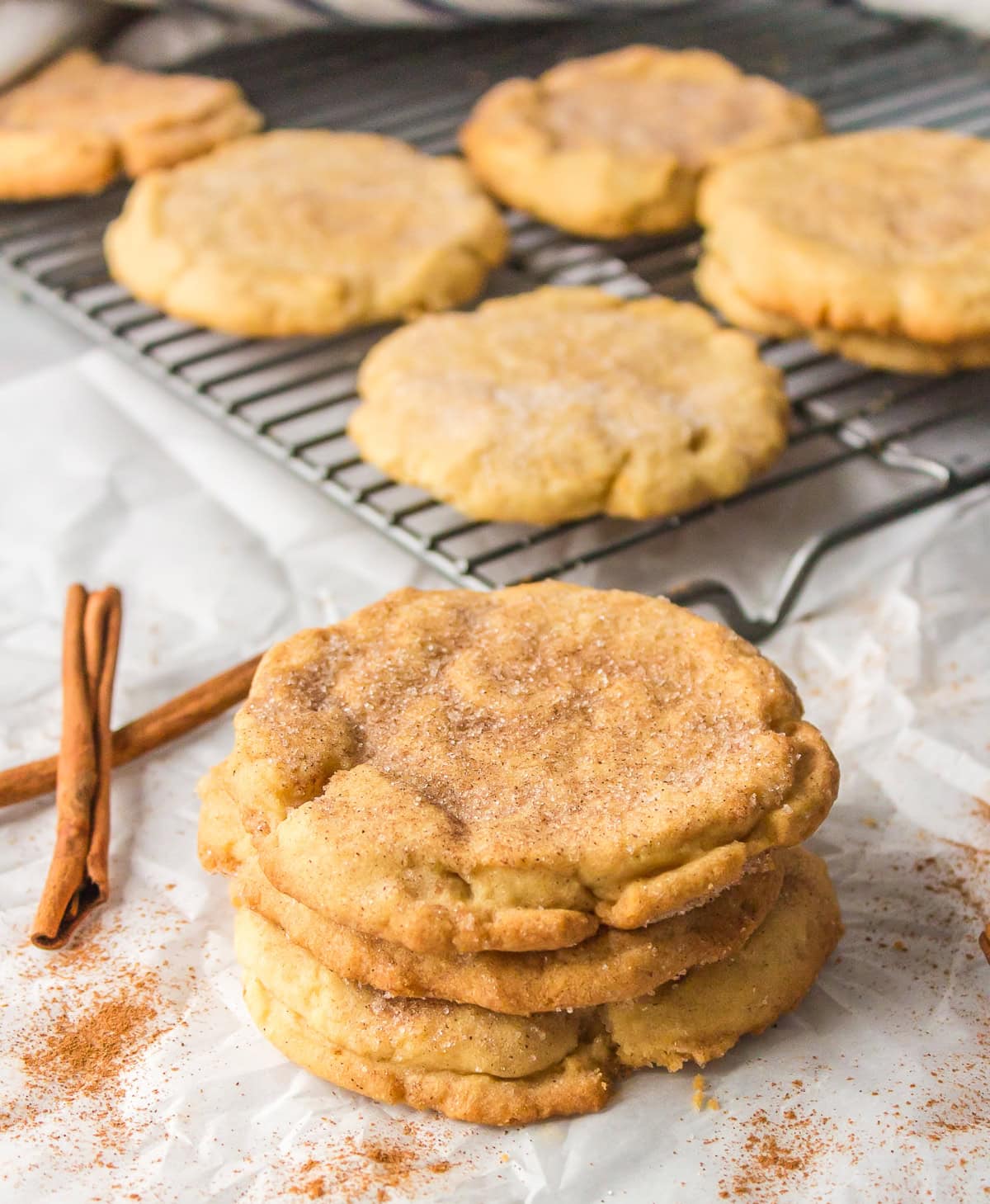 stack of sugar and cinnamon cookies with more on cooling rack
