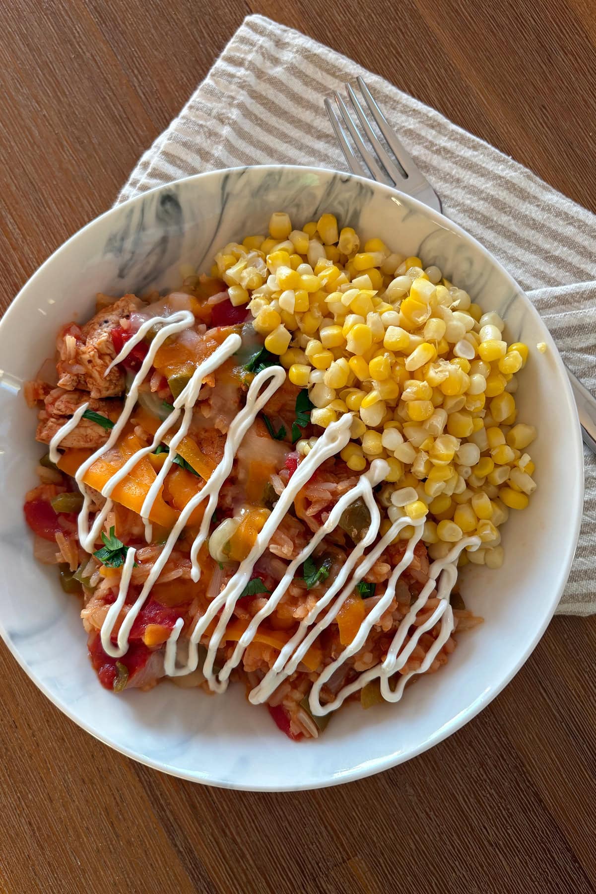 This easy Arroz con Pollo is a flavorful one-pan chicken and rice dinner that's ready in only 45 minutes! Made with juicy chicken, rice, tomatoes and peppers, it's the perfect family-friendly weeknight meal. arroz con pollo in bowl with sour cream