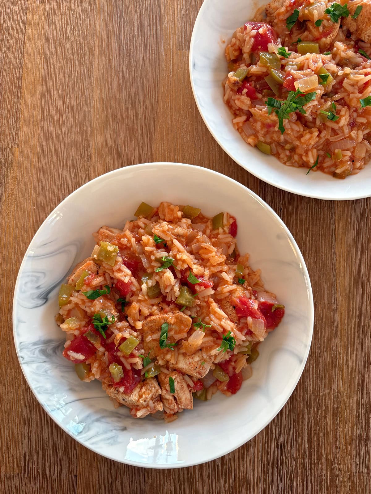 This easy Arroz con Pollo is a flavorful one-pan chicken and rice dinner that's ready in only 45 minutes! Made with juicy chicken, rice, tomatoes and peppers, it's the perfect family-friendly weeknight meal. arroz con pollo in two dishes