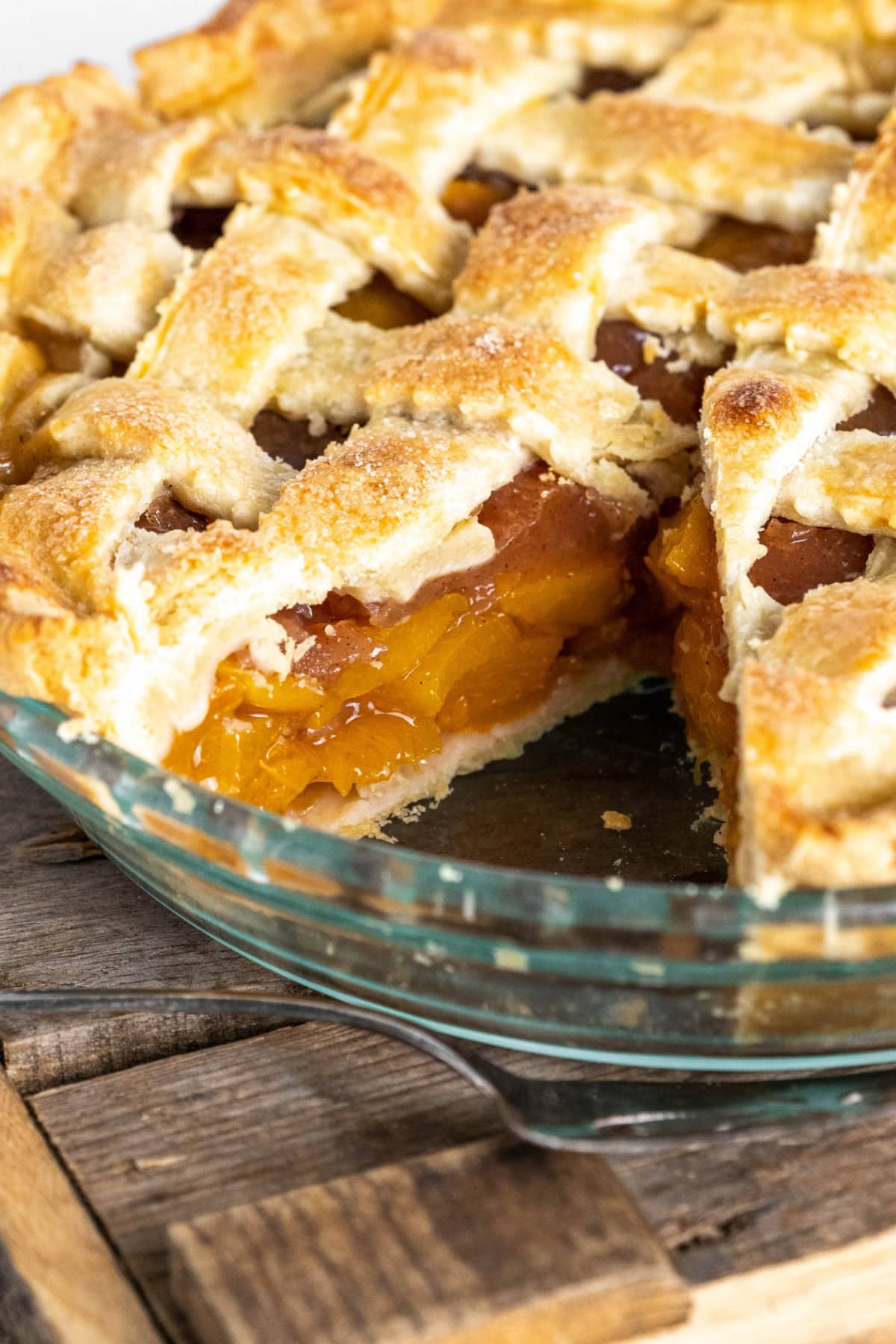This Fresh Peach Pie Recipe is everything summer baking should be! 🍑 Made with juicy ripe peaches, a flaky homemade butter crust and a gorgeous lattice top, this classic pie is perfect for holidays, BBQs and family gatherings. Save this recipe for peach season! #peachpie #freshpeaches #summerdesserts #pierecipe #homemadepie fresh peach pie with a big slice taken out of it
