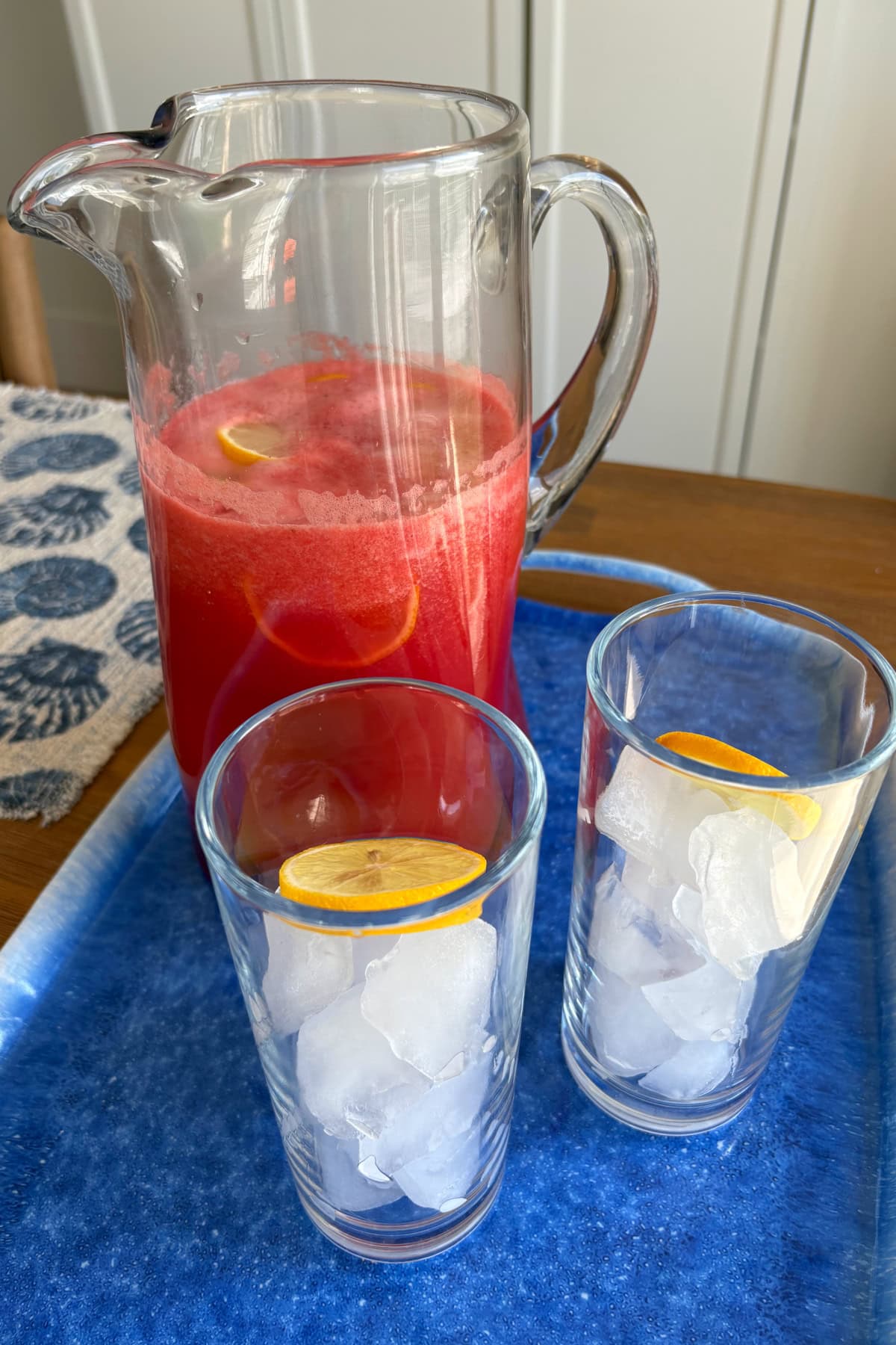 pitcher of watermelon strawberry lemonade with two ice filled glasses