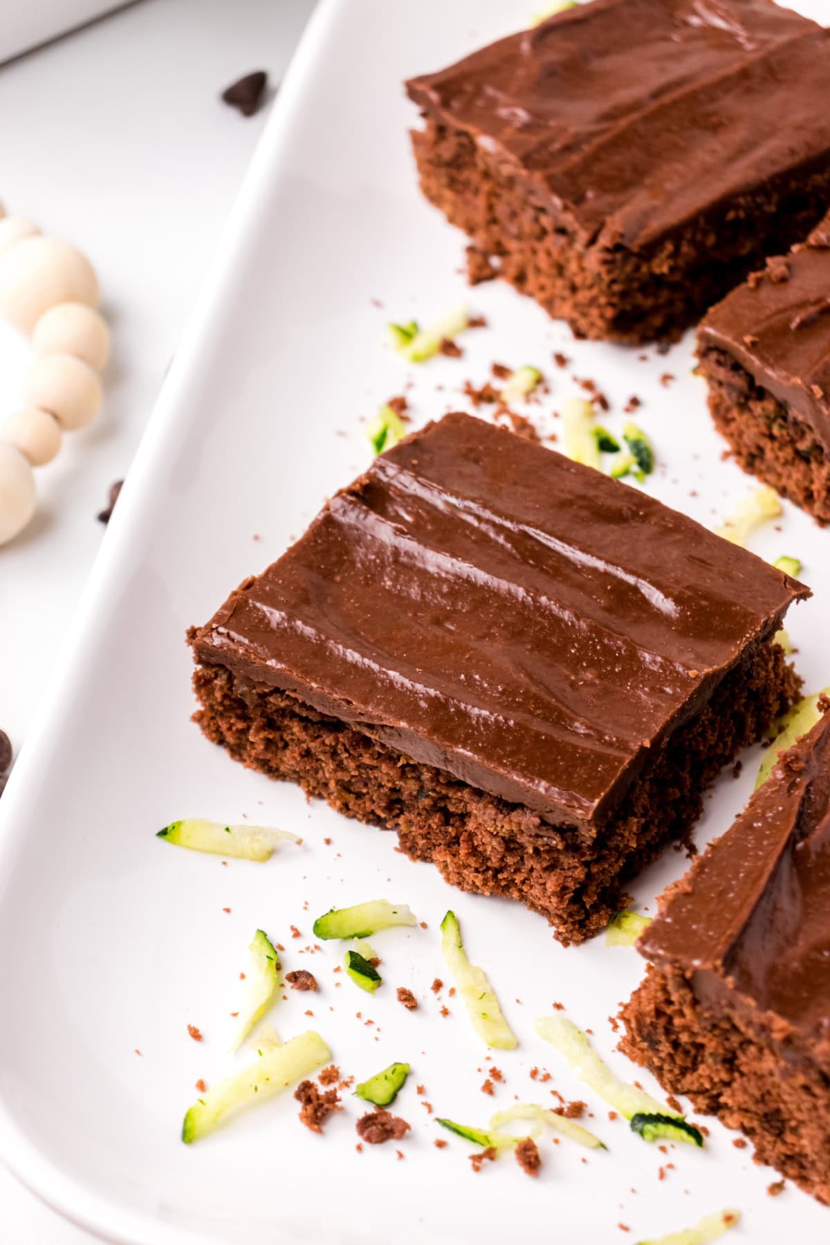 This Chocolate Zucchini Cake is unbelievably moist and rich with chocolate flavor! 🍫 Fresh zucchini keeps the cake soft and tender, while an old-fashioned chocolate marshmallow frosting makes every bite irresistible. Save this easy summer baking recipe! #zucchinicake #chocolatecake #zucchinirecipes #summerbaking #dessertrecipes slices of chocolate zucchini cake