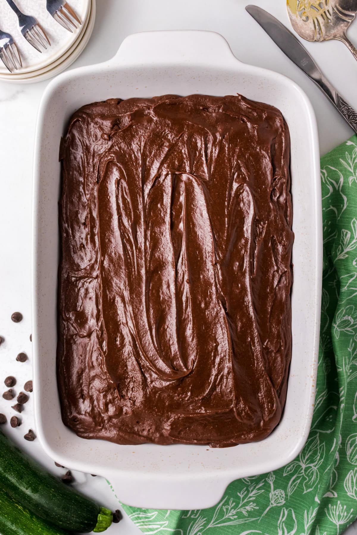This Chocolate Zucchini Cake is unbelievably moist and rich with chocolate flavor! 🍫 Fresh zucchini keeps the cake soft and tender, while an old-fashioned chocolate marshmallow frosting makes every bite irresistible. Save this easy summer baking recipe! #zucchinicake #chocolatecake #zucchinirecipes #summerbaking #dessertrecipes frosted chocolate zucchini cake
