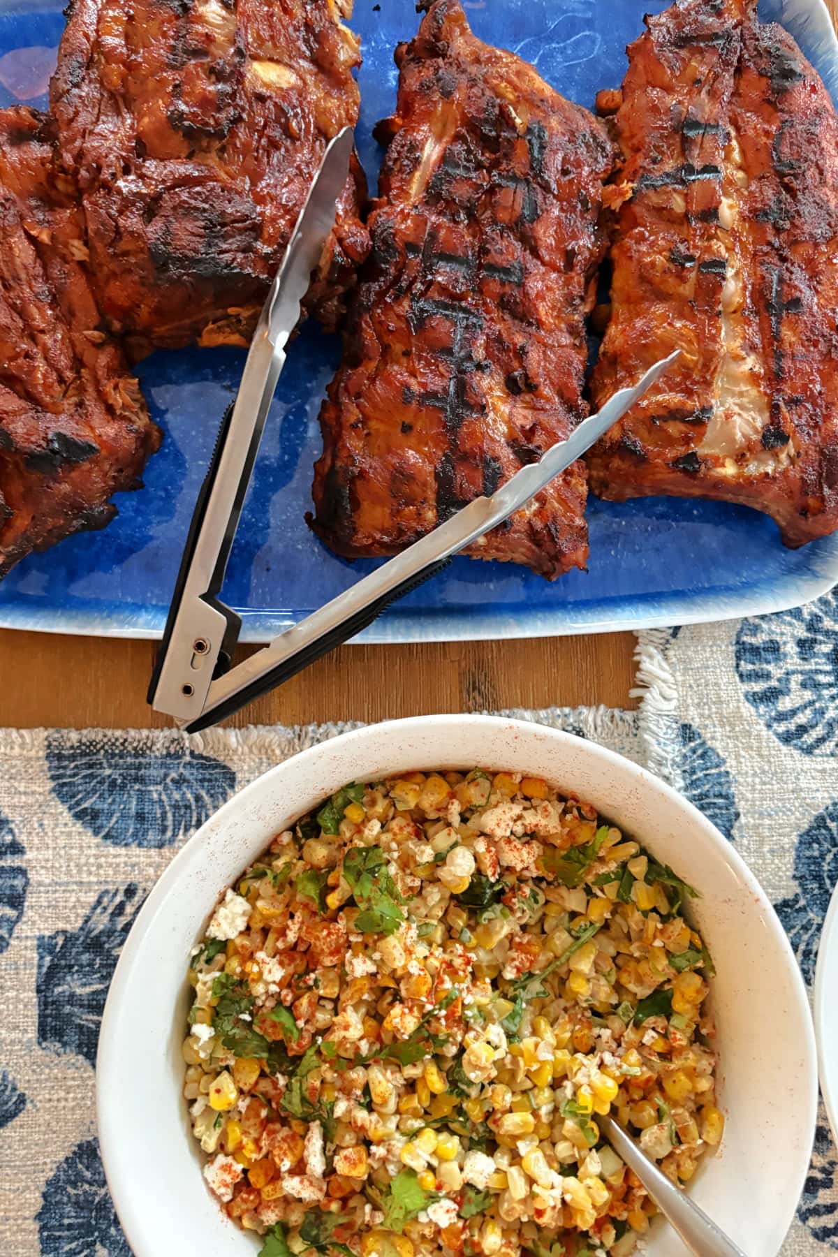 These Dr. Pepper Ribs are fall-apart tender and loaded with flavor! Baby back ribs are marinated in Dr. Pepper, baked until tender and finished on the grill with a sticky homemade Dr. Pepper BBQ sauce. An easy rib recipe for summer cookouts, Father's Day and backyard BBQs. dr. pepper ribs on platter with corn salad on side