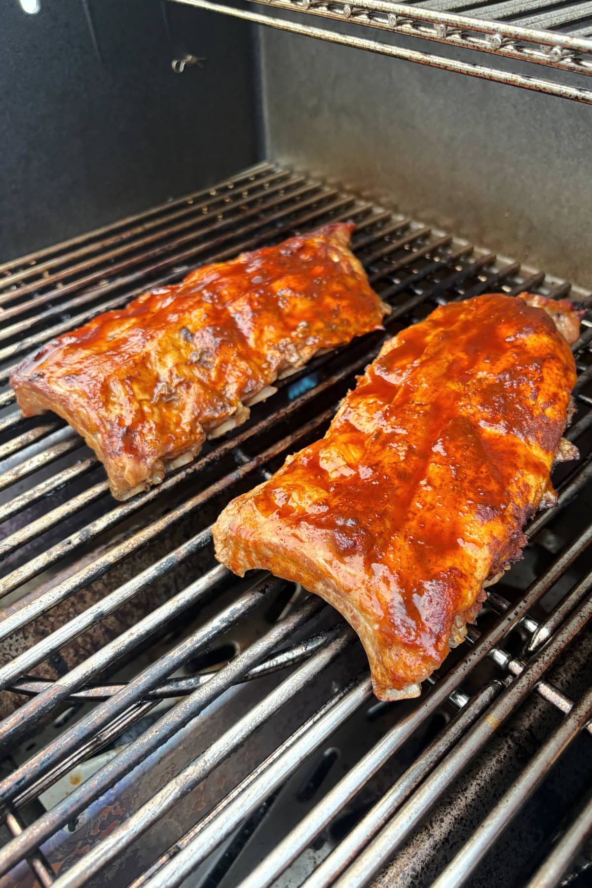 These Dr. Pepper Ribs are fall-apart tender and loaded with flavor! Baby back ribs are marinated in Dr. Pepper, baked until tender and finished on the grill with a sticky homemade Dr. Pepper BBQ sauce. An easy rib recipe for summer cookouts, Father's Day and backyard BBQs. dr. pepper ribs on grill