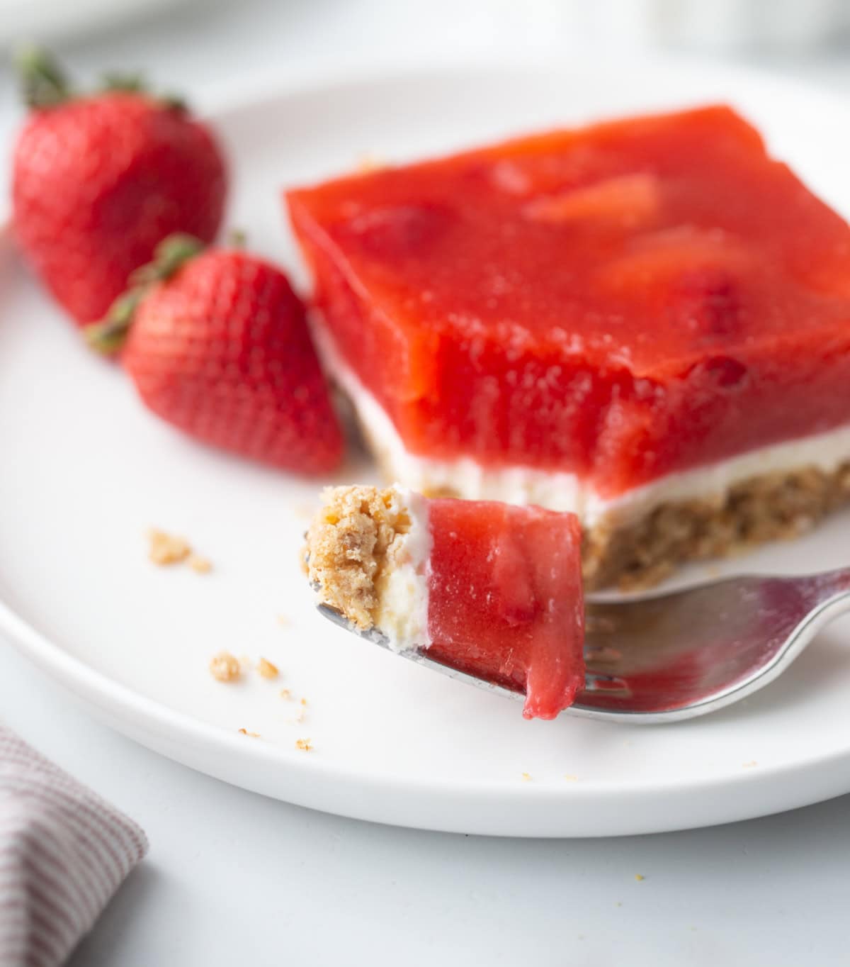 This Old Fashioned Strawberry Pretzel Salad is a timeless favorite! 🍓 Made with a buttery pretzel crust, fluffy cream cheese layer and a homemade strawberry topping with real strawberries, it's the perfect make-ahead dessert for holidays, potlucks and summer parties. Save this classic recipe! #strawberrypretzelsalad #strawberrydessert #potluckrecipes #summerdesserts #vintagerecipes fork full of old fashioned strawberry pretzel salad
