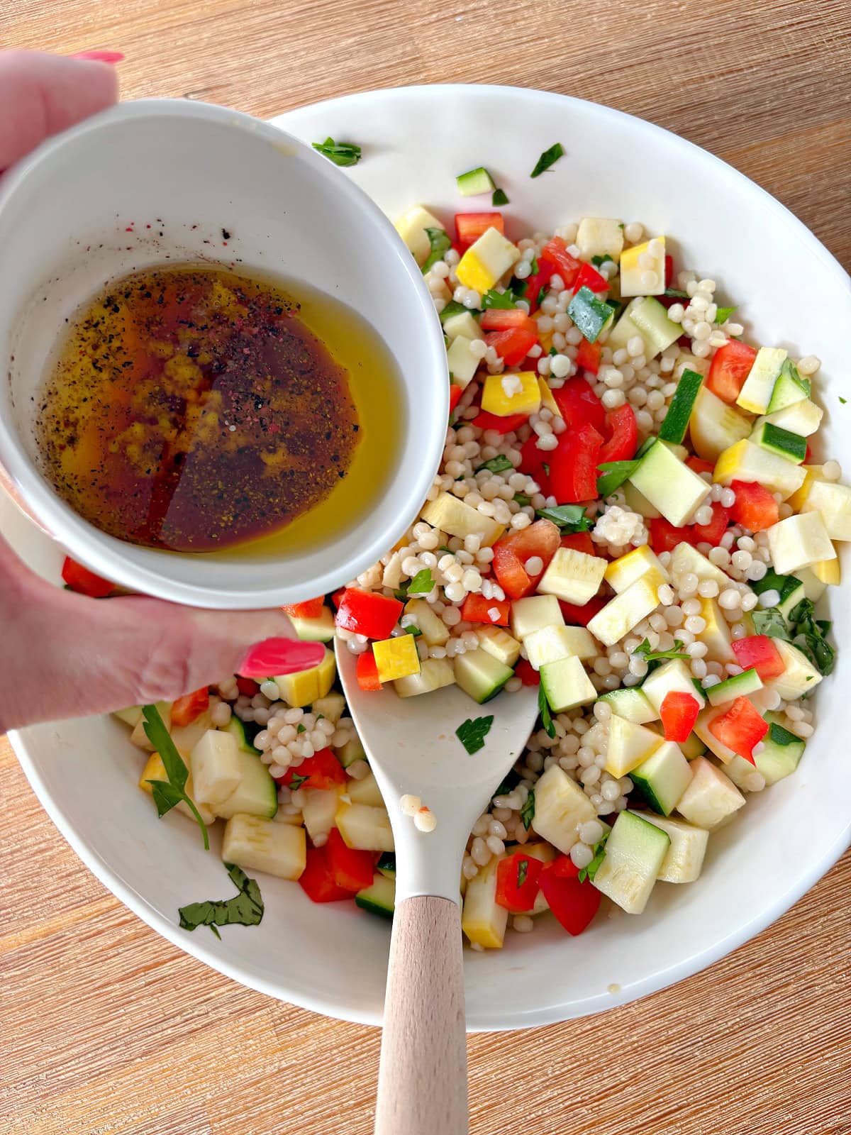 summer couscous salad with dressing being added