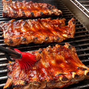 Brushing sauce onto Dr. Pepper Ribs on grill