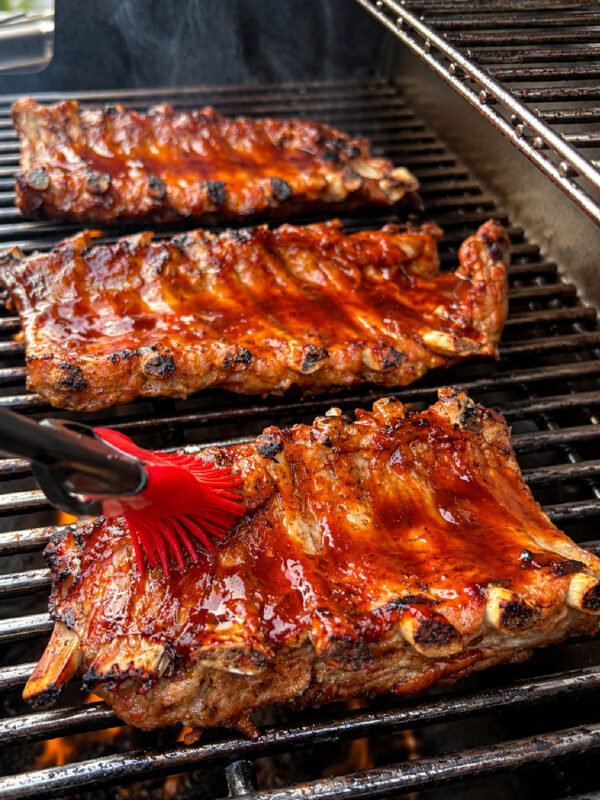 Brushing sauce onto Dr. Pepper Ribs on grill