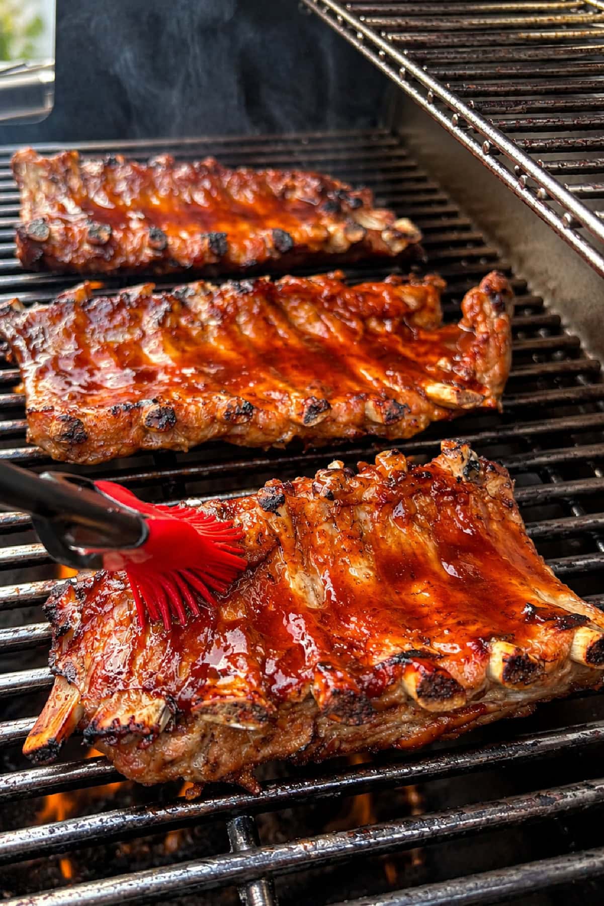 Brushing sauce onto Dr. Pepper Ribs on grill