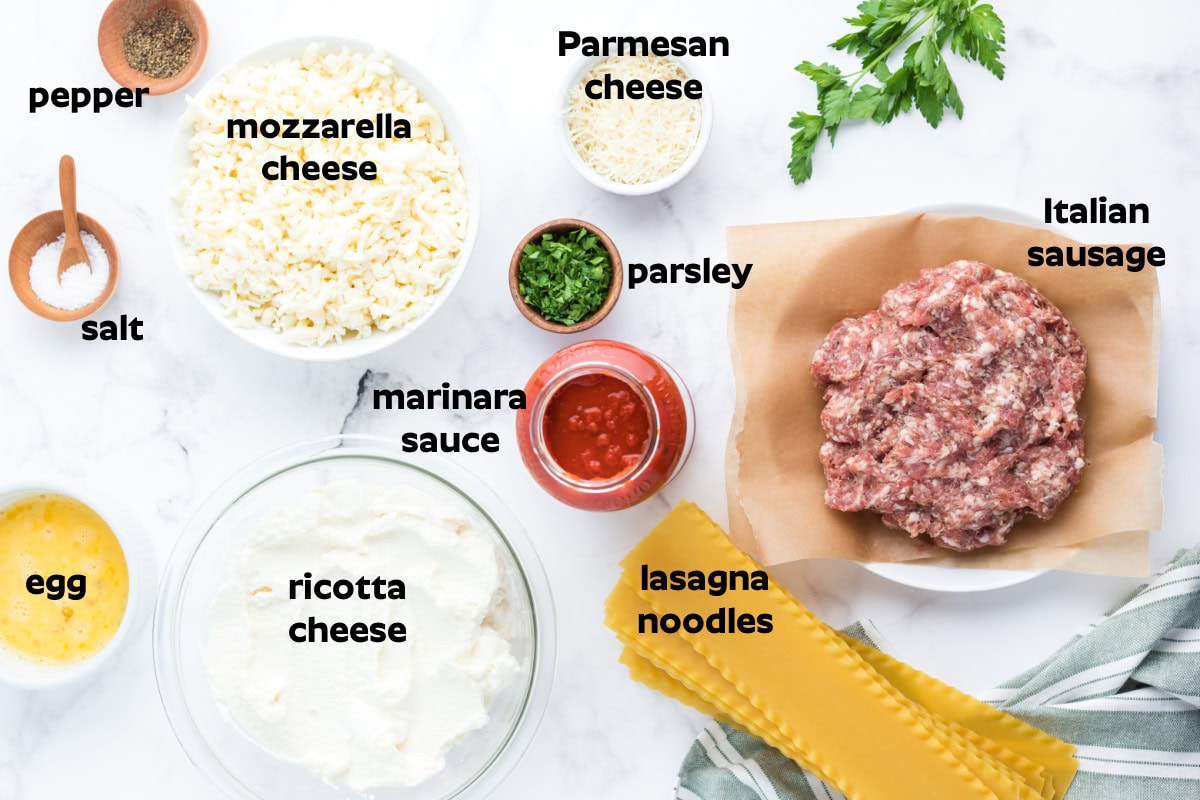 These easy Italian Sausage Lasagna Roll Ups are filled with ricotta, Parmesan and mozzarella, rolled up and baked in a hearty Italian sausage marinara sauce. A cheesy, comforting family dinner that's easy to make ahead and freezer-friendly, too! Save this easy lasagna recipe for weeknight dinners, Sunday supper or entertaining. Ingredients displayed for making Italian Sausage Lasagna roll Ups