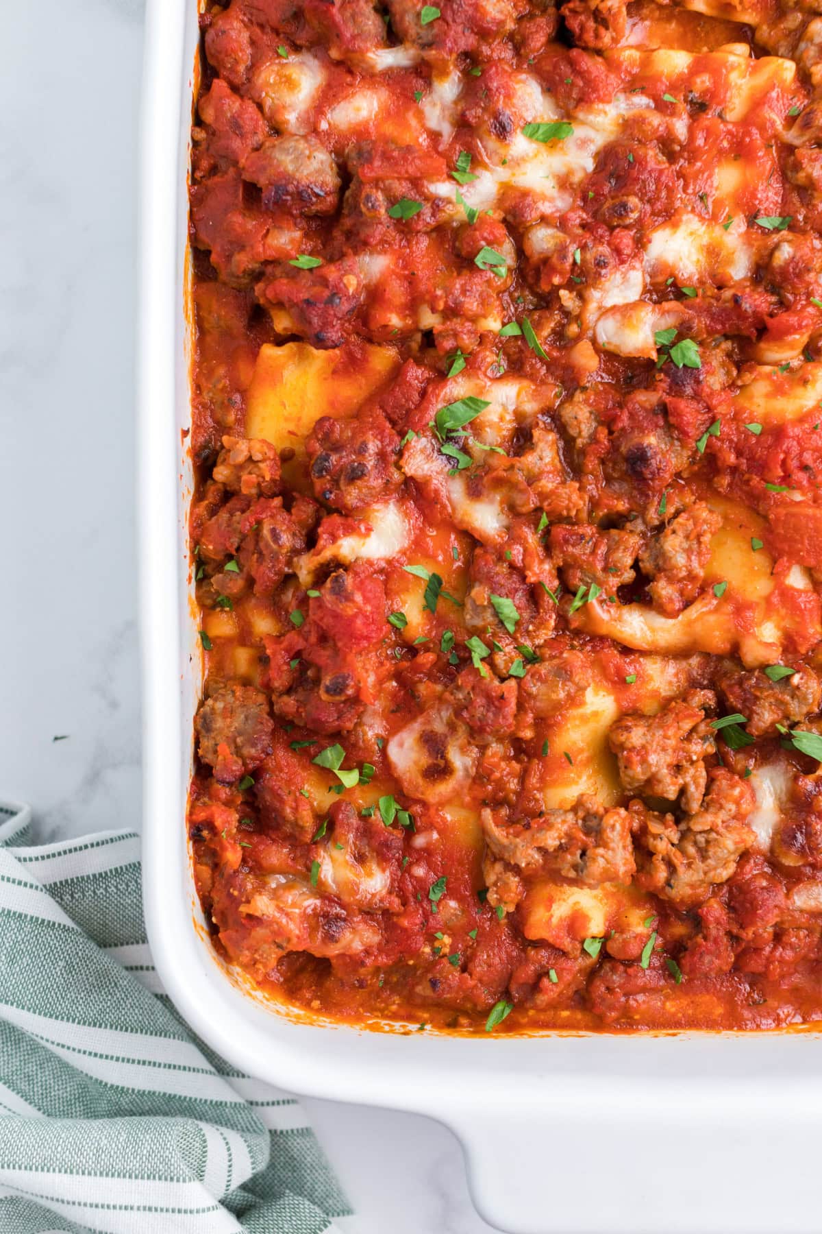 These easy Italian Sausage Lasagna Roll Ups are filled with ricotta, Parmesan and mozzarella, rolled up and baked in a hearty Italian sausage marinara sauce. A cheesy, comforting family dinner that's easy to make ahead and freezer-friendly, too! Save this easy lasagna recipe for weeknight dinners, Sunday supper or entertaining. close up dish of Italian Sausage Lasagna Roll Ups