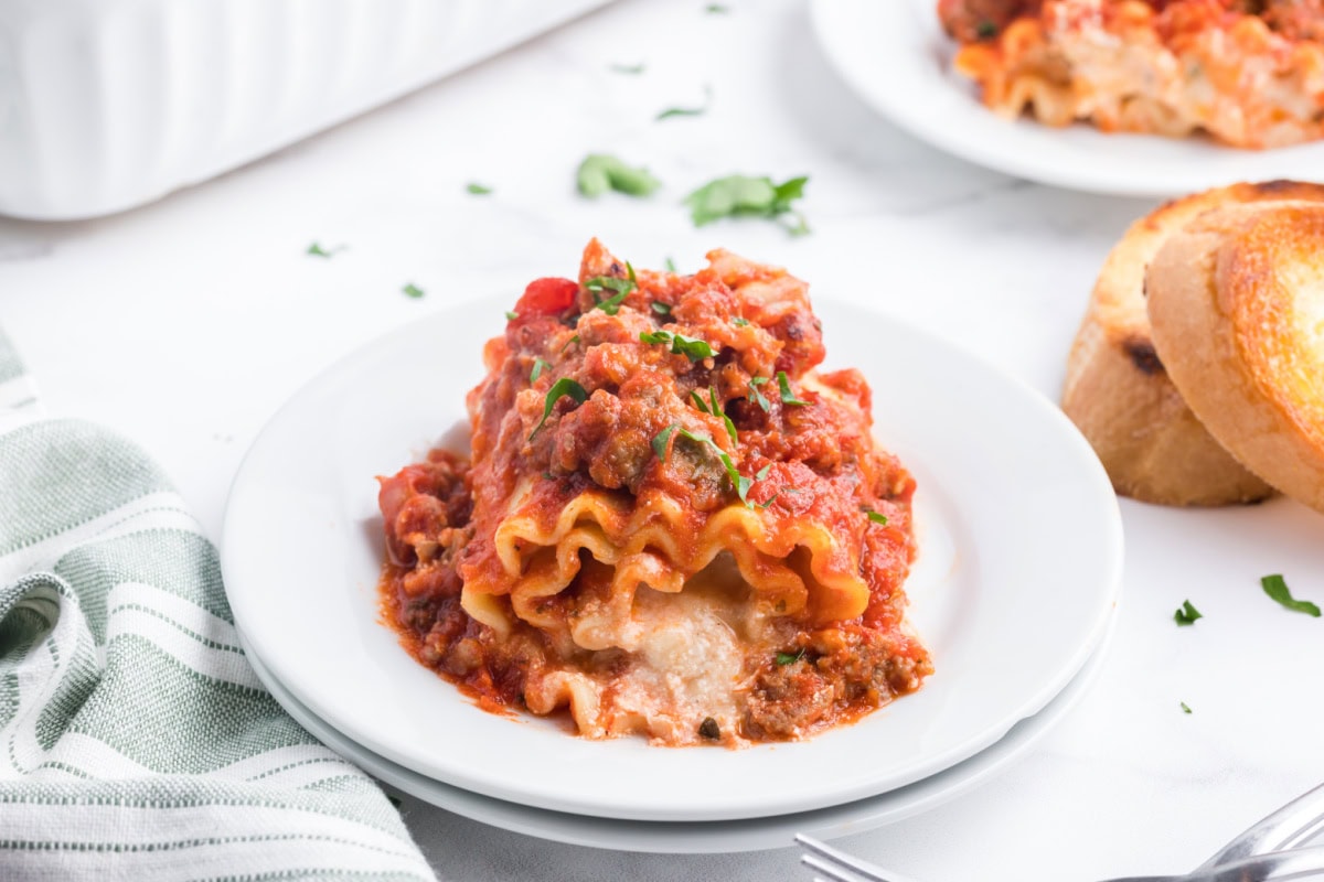 These easy Italian Sausage Lasagna Roll Ups are filled with ricotta, Parmesan and mozzarella, rolled up and baked in a hearty Italian sausage marinara sauce. A cheesy, comforting family dinner that's easy to make ahead and freezer-friendly, too! Save this easy lasagna recipe for weeknight dinners, Sunday supper or entertaining. serving of Italian Sausage Lasagna Roll Ups