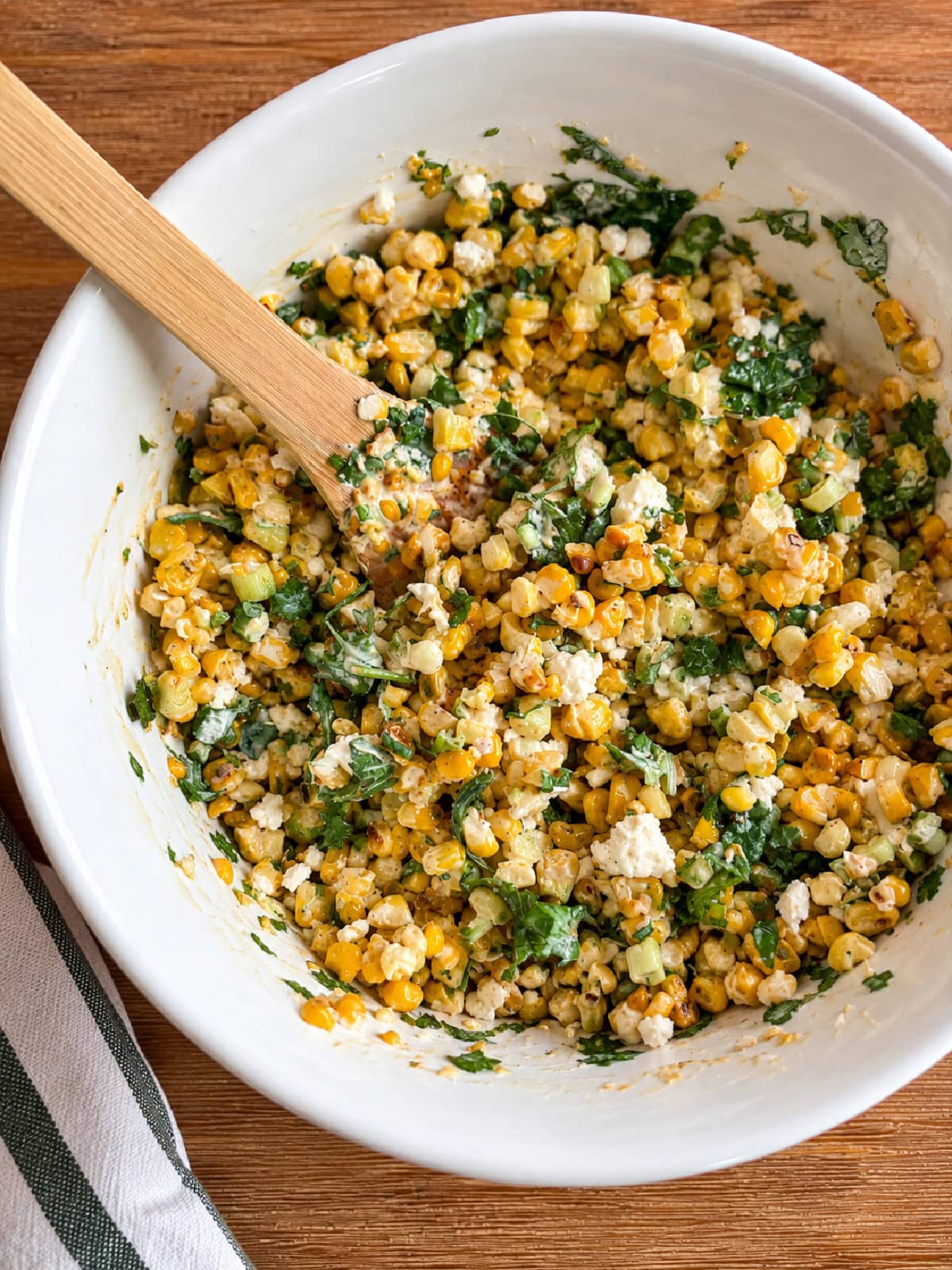 This easy Mexican Street Corn Salad combines lightly charred corn with Cotija cheese, cilantro, green onions and a creamy lime dressing. Make it with fresh, frozen or canned corn for an easy summer side dish that's perfect for tacos, BBQs, potlucks and cookouts. mexican street corn salad mixed in bowl