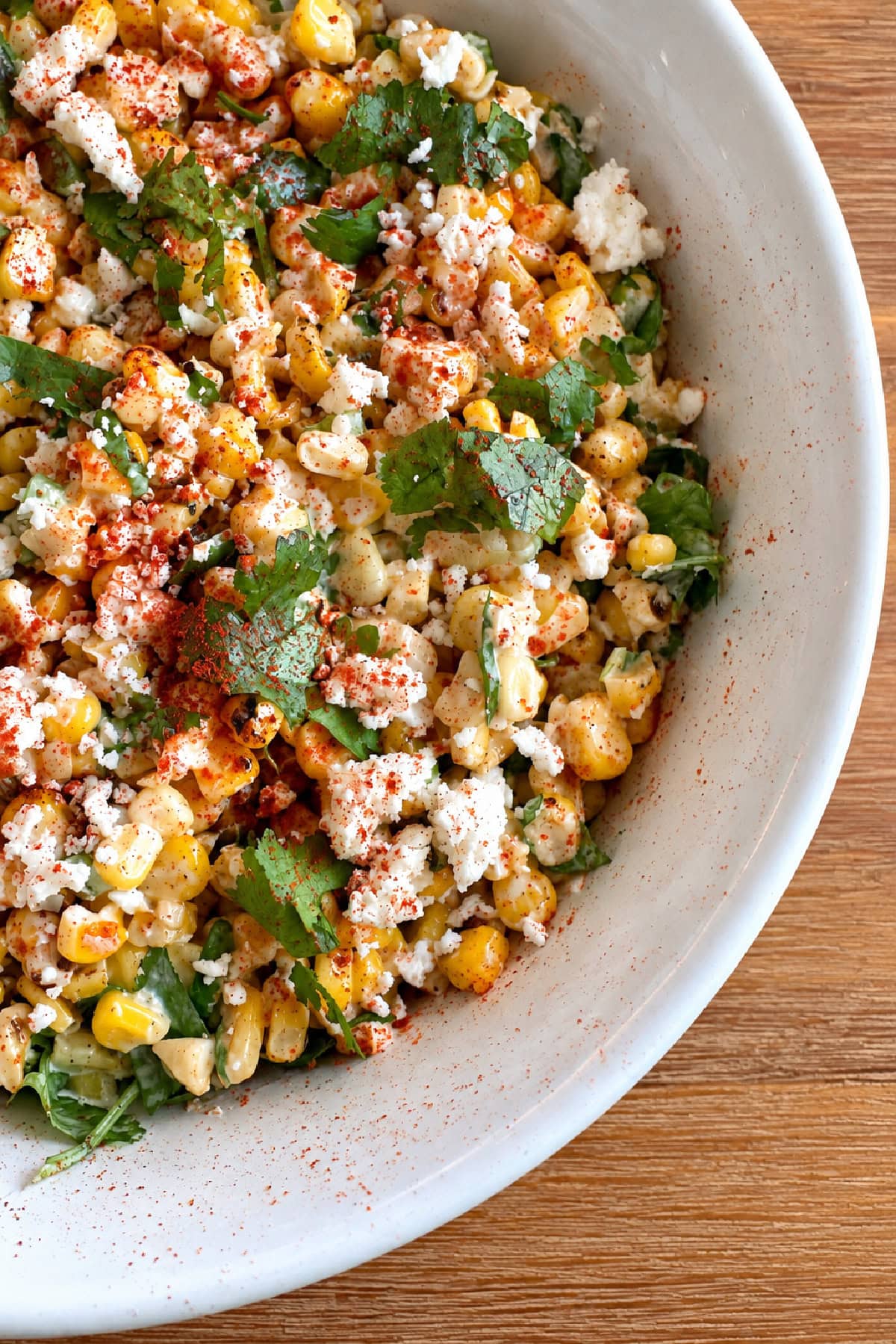 This easy Mexican Street Corn Salad combines lightly charred corn with Cotija cheese, cilantro, green onions and a creamy lime dressing. Make it with fresh, frozen or canned corn for an easy summer side dish that's perfect for tacos, BBQs, potlucks and cookouts. side peek at mexican street corn salad