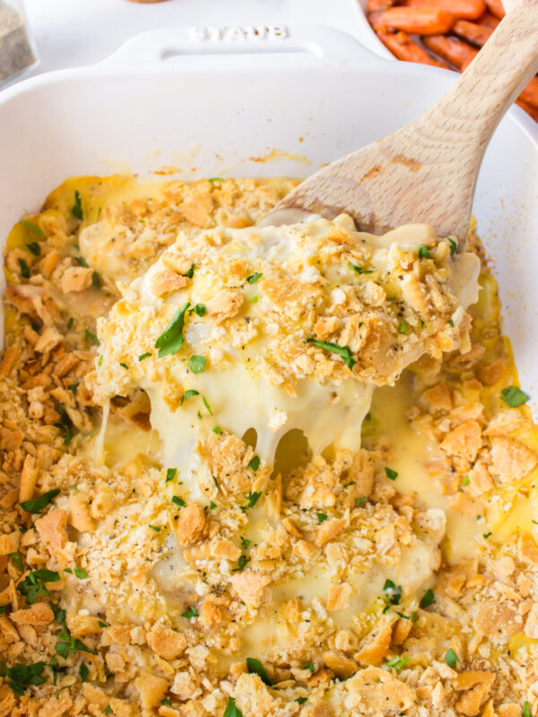 swiss cheese chicken in casserole dish with spoon taking out cheesy serving