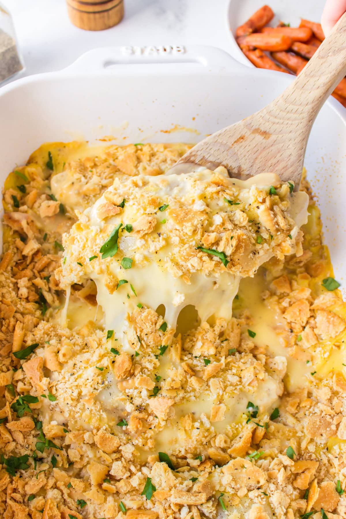 This easy Swiss Cheese Chicken recipe is the perfect comfort-food dinner! Chicken breasts are topped with Swiss cheese, a creamy sauce and buttery Ritz cracker crumbs, then baked until tender and golden. An easy 45-minute chicken dinner that's great for busy weeknights. swiss cheese chicken in casserole dish with spoon taking out cheesy serving