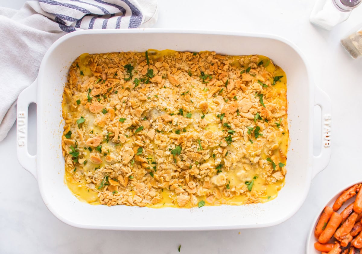 This easy Swiss Cheese Chicken recipe is the perfect comfort-food dinner! Chicken breasts are topped with Swiss cheese, a creamy sauce and buttery Ritz cracker crumbs, then baked until tender and golden. An easy 45-minute chicken dinner that's great for busy weeknights. white casserole dish of swiss cheese chicken