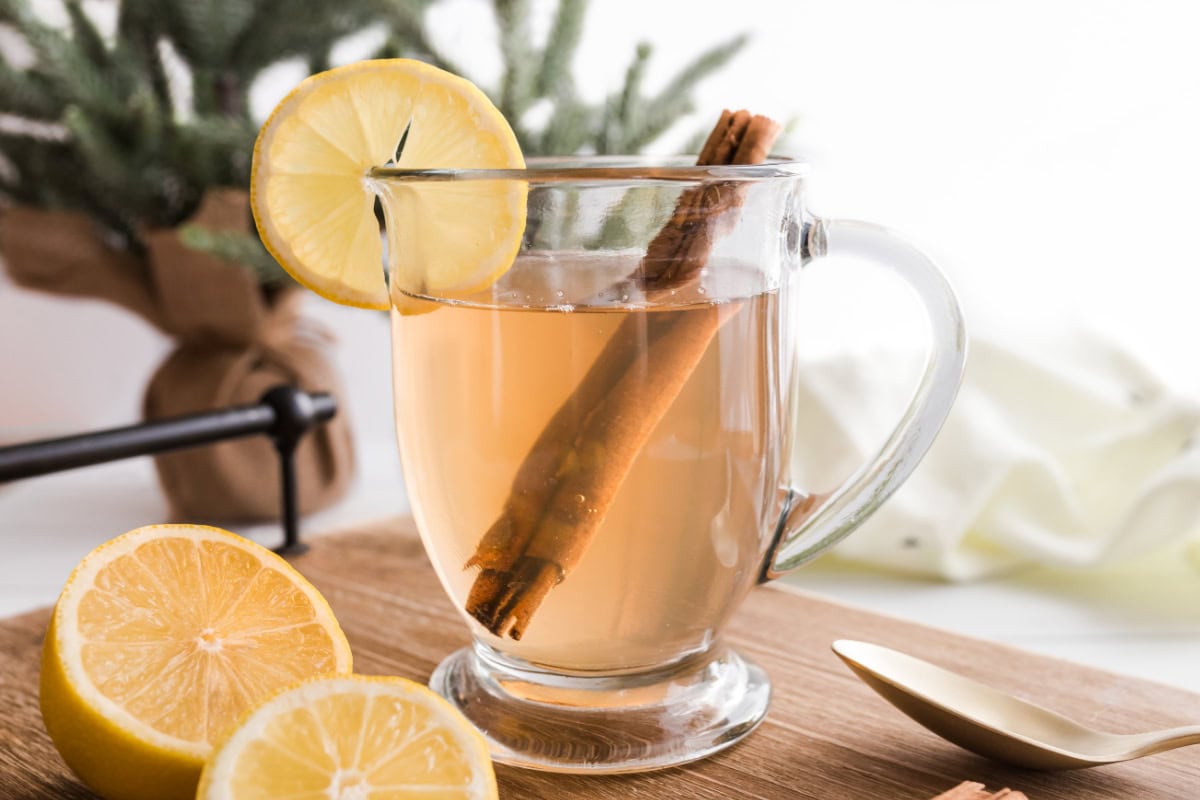 side view of a hot toddy garnished with lemon and cinnamon stick