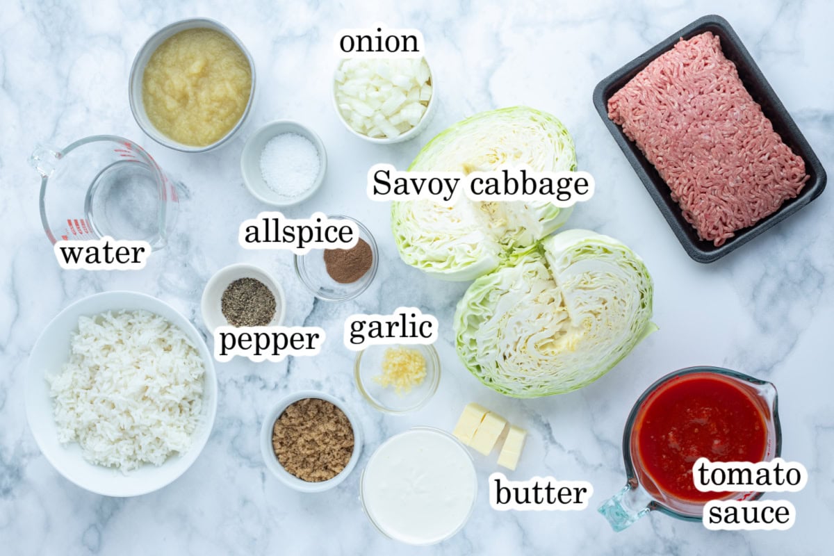 These homemade Polish Cabbage Rolls (Golabki) are the ultimate comfort food! Tender Savoy cabbage leaves are filled with ground beef, rice and seasoned tomato sauce, then baked until tender. Serve with sour cream and applesauce for a delicious old-fashioned family dinner. Save this recipe for a cozy weekend meal! ingredients displayed for making polish cabbage rolls