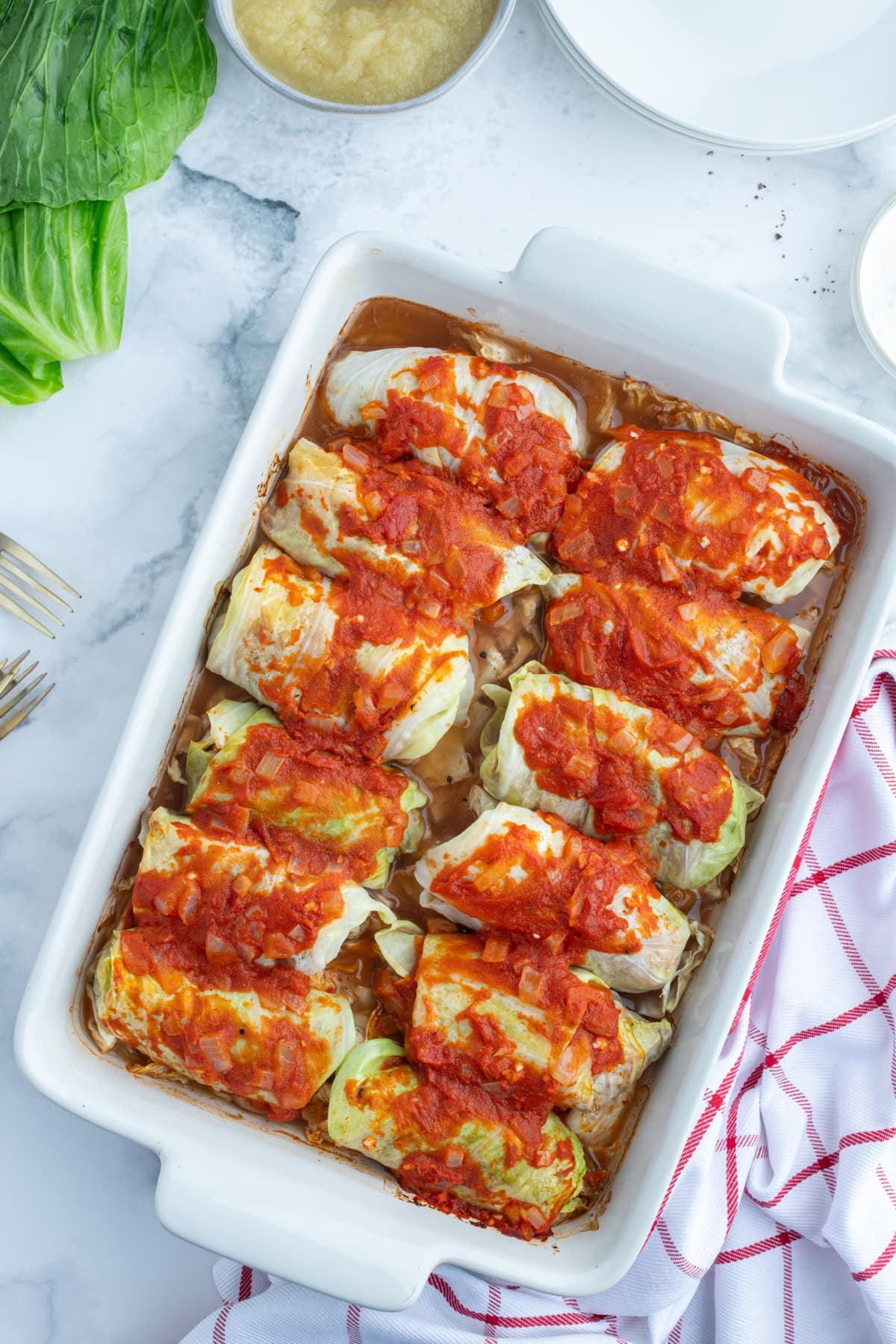 These homemade Polish Cabbage Rolls (Golabki) are the ultimate comfort food! Tender Savoy cabbage leaves are filled with ground beef, rice and seasoned tomato sauce, then baked until tender. Serve with sour cream and applesauce for a delicious old-fashioned family dinner. Save this recipe for a cozy weekend meal! stuffed polish cabbage rolls in a casserole dish